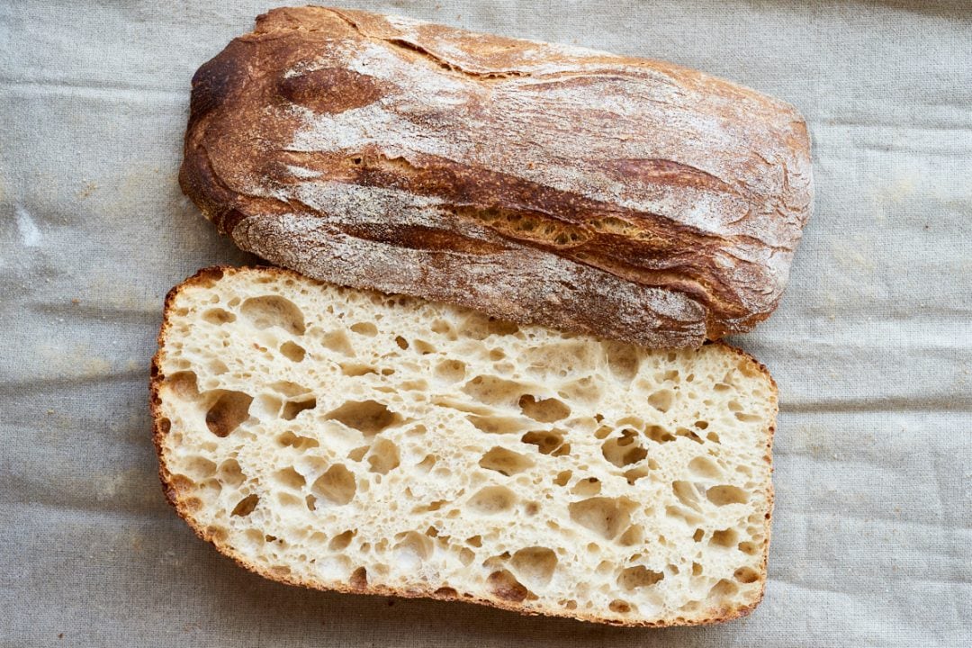 Sourdough ciabatta cut open on table.