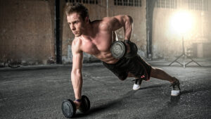 a man demonstrating the Renegade row exercise with a pair of dumbbells